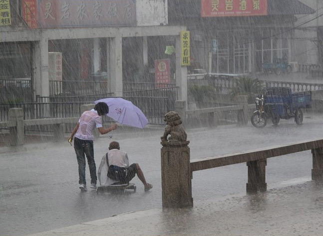 女孩冒雨为残疾乞丐撑伞获赞 躲雨"制服男"遭斥